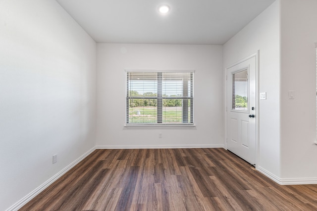 spare room with baseboards and dark wood finished floors