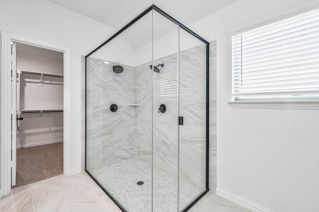 bathroom with baseboards, a marble finish shower, marble finish floor, and a walk in closet