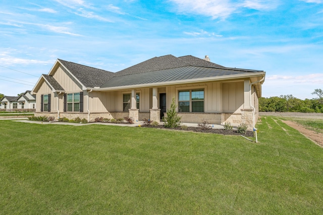 view of front of property featuring stone siding, a standing seam roof, a front lawn, and board and batten siding