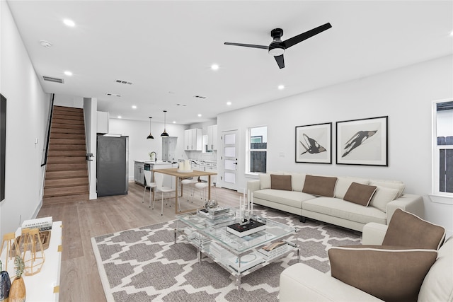 living room with light hardwood / wood-style floors and ceiling fan