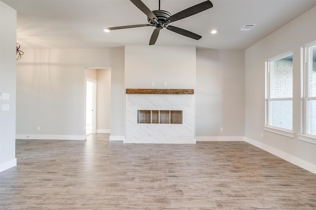 unfurnished living room featuring ceiling fan, light wood-type flooring, and a fireplace