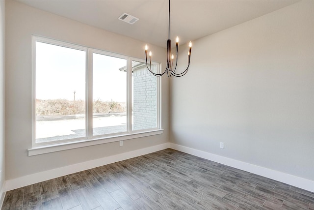 unfurnished dining area featuring a chandelier and hardwood / wood-style floors