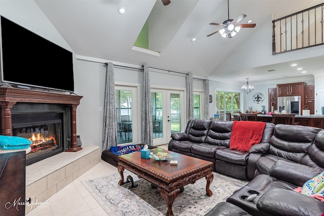 tiled living room featuring french doors, crown molding, high vaulted ceiling, a tiled fireplace, and ceiling fan with notable chandelier