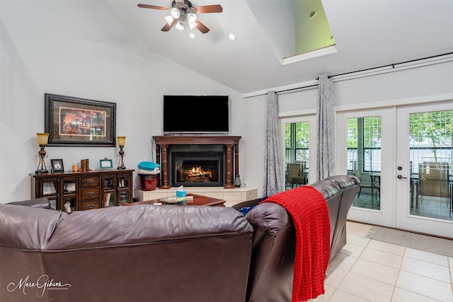 tiled living room with french doors, a tiled fireplace, lofted ceiling, and ceiling fan