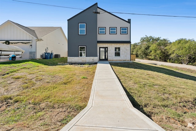 view of front of house featuring a garage, cooling unit, and a front yard