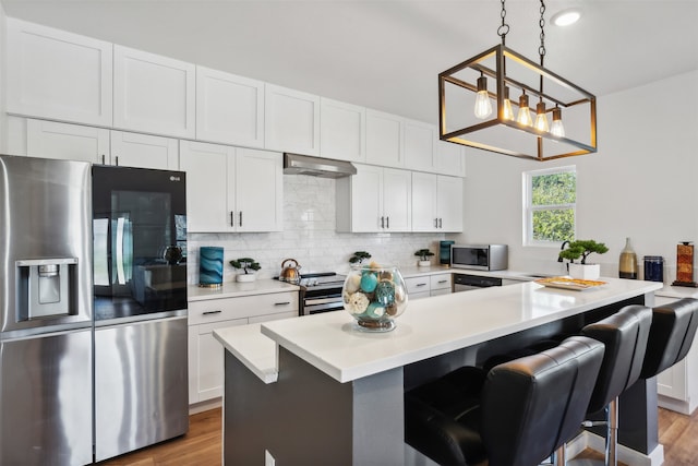 kitchen with a breakfast bar area, white cabinetry, and appliances with stainless steel finishes