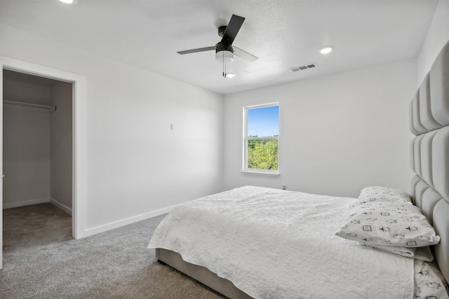 bedroom with a walk in closet, ceiling fan, and carpet floors