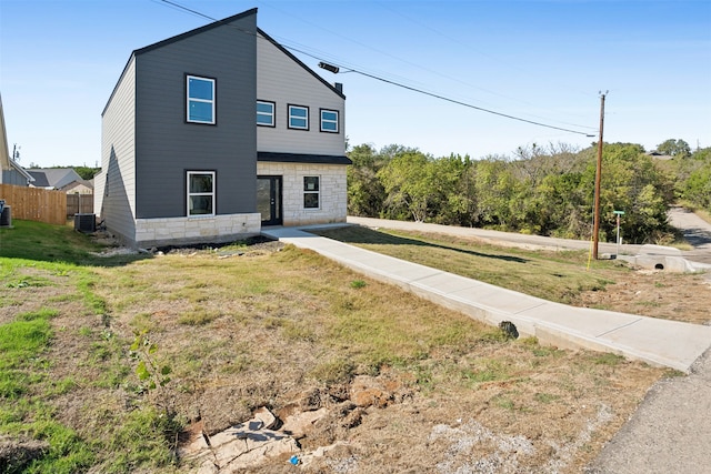 view of front of property with a front lawn and central AC