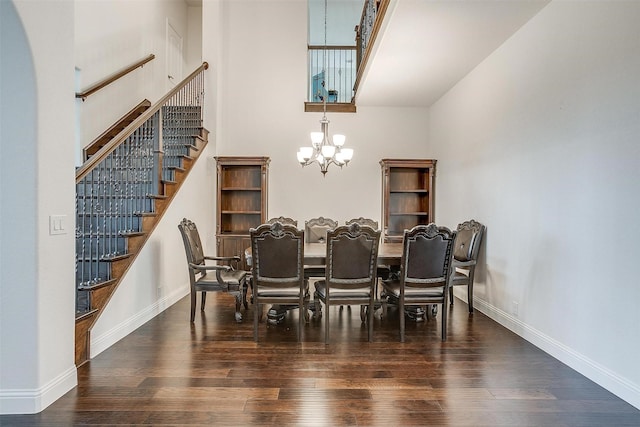 dining area with a high ceiling, an inviting chandelier, wood finished floors, and baseboards