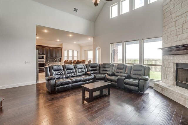 living room with ceiling fan, high vaulted ceiling, and dark wood-type flooring