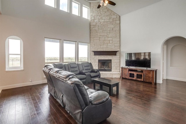 living room featuring dark wood-style floors, arched walkways, ceiling fan, and baseboards