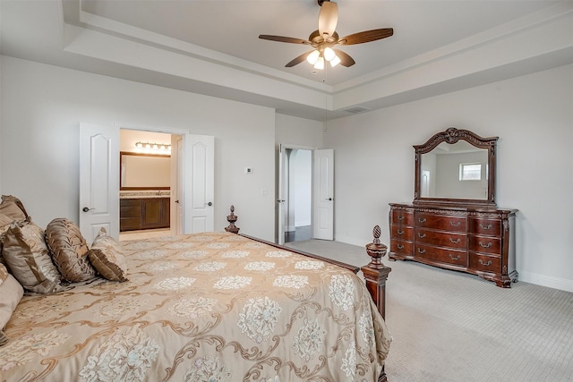 carpeted bedroom with ensuite bath, a raised ceiling, and ceiling fan