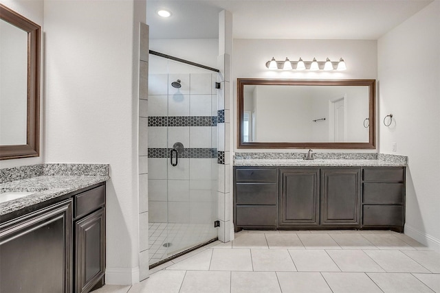 full bath with a sink, a stall shower, two vanities, and tile patterned floors