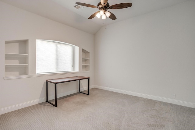 unfurnished office featuring built in shelves, visible vents, light carpet, vaulted ceiling, and baseboards