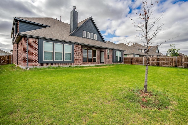 back of house with a yard, brick siding, and fence