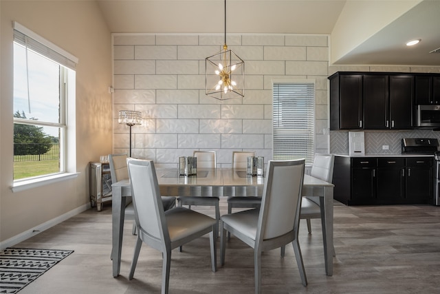 dining space featuring an inviting chandelier, light wood-type flooring, and lofted ceiling