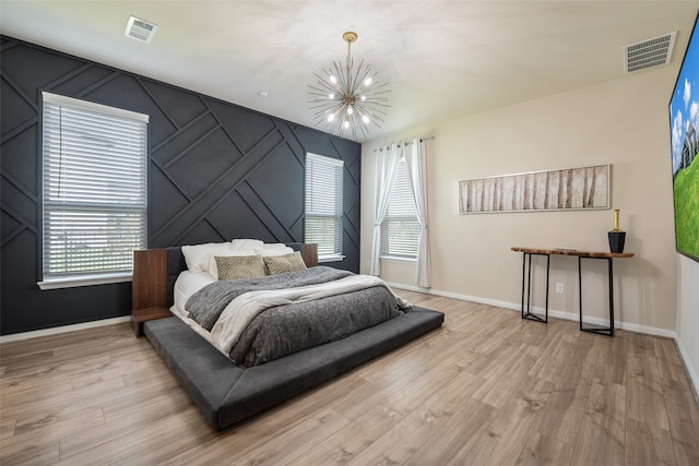 bedroom with light hardwood / wood-style floors and a chandelier