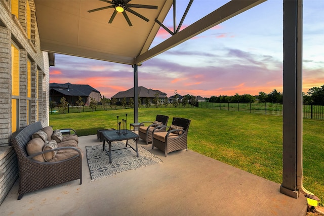 patio terrace at dusk with an outdoor hangout area, a lawn, and ceiling fan