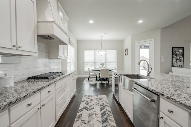 kitchen with white cabinets, appliances with stainless steel finishes, light stone counters, and pendant lighting