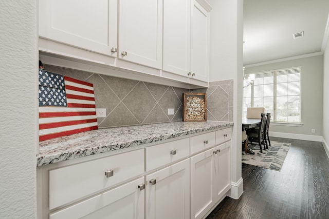 kitchen featuring decorative backsplash, light stone counters, dark wood-type flooring, crown molding, and white cabinets