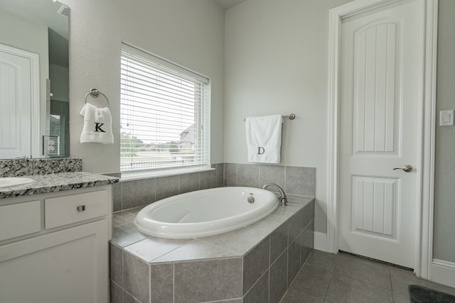 bathroom featuring tile patterned flooring, vanity, and tiled tub