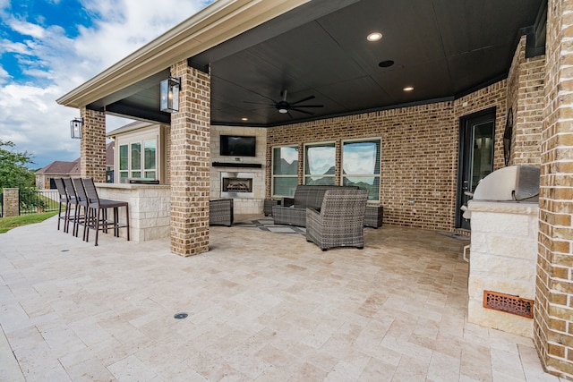 view of patio featuring an outdoor living space with a fireplace, ceiling fan, exterior kitchen, and exterior bar