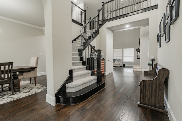 entrance foyer featuring hardwood / wood-style flooring, a towering ceiling, and crown molding