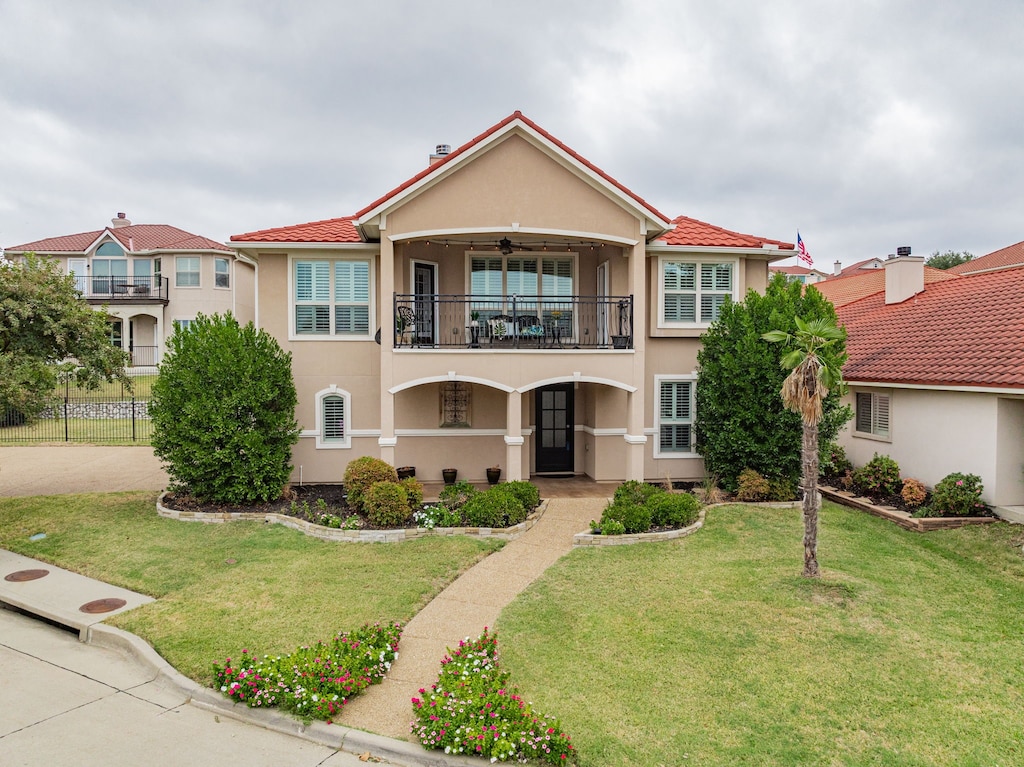 mediterranean / spanish home with a front lawn, ceiling fan, and a balcony