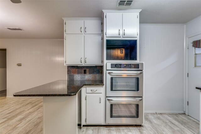 kitchen featuring light wood-style flooring, double oven, white cabinetry, visible vents, and a peninsula