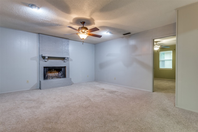 unfurnished living room with a textured ceiling, light carpet, ceiling fan, and a brick fireplace