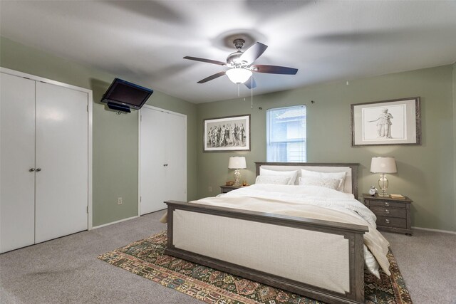 bedroom with multiple closets, baseboards, a ceiling fan, and carpet flooring