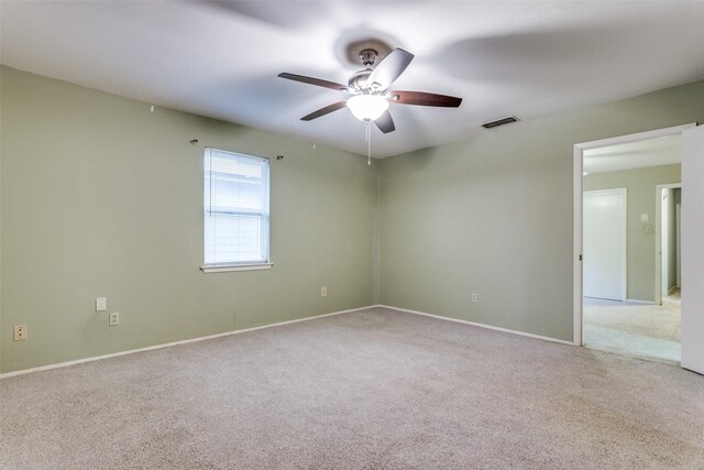 carpeted spare room featuring visible vents, a ceiling fan, and baseboards