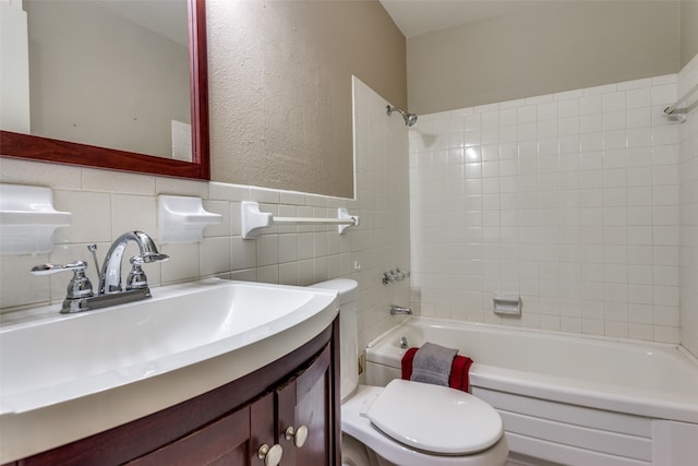 full bathroom with tile walls, vanity, tiled shower / bath combo, and toilet