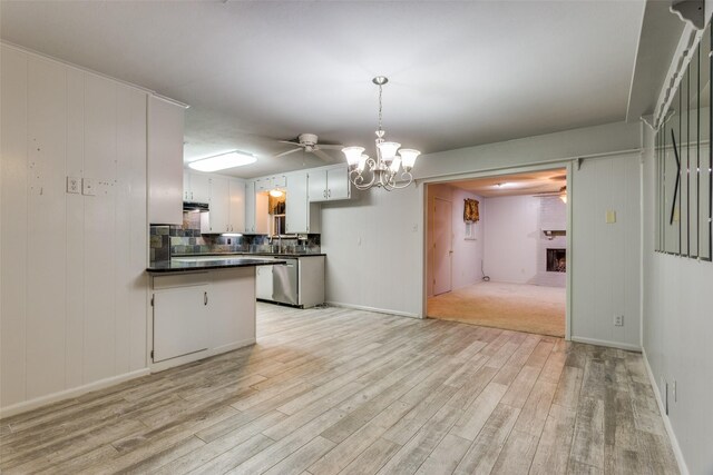 kitchen featuring dark countertops, light wood-style floors, a brick fireplace, and an inviting chandelier
