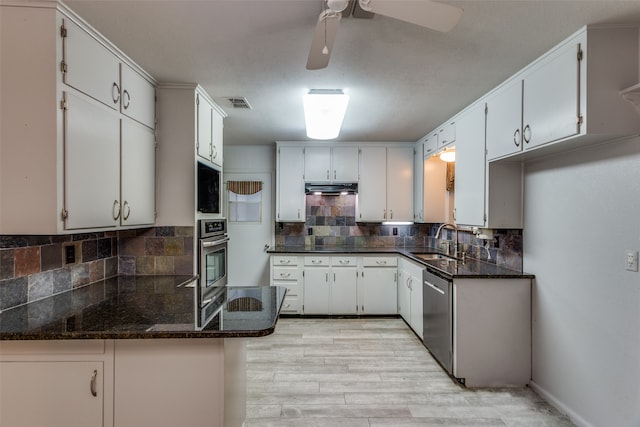 kitchen with white cabinets, light hardwood / wood-style floors, dark stone counters, and appliances with stainless steel finishes