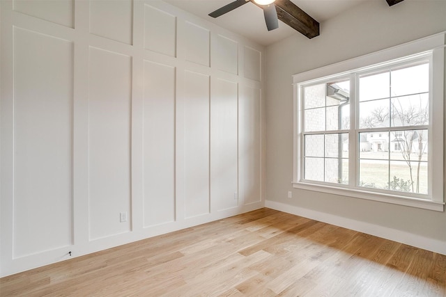 spare room featuring light wood finished floors, beamed ceiling, ceiling fan, and baseboards