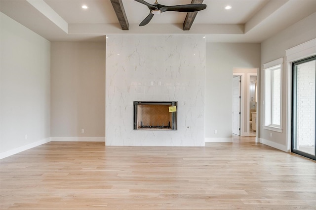 unfurnished living room with plenty of natural light, baseboards, light wood-style floors, and a high end fireplace