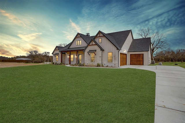 modern farmhouse style home with a front yard, driveway, an attached garage, a shingled roof, and board and batten siding