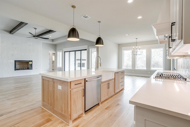 kitchen with light wood finished floors, light brown cabinetry, a premium fireplace, stainless steel appliances, and a sink