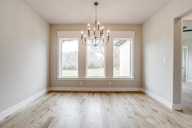 unfurnished dining area with a chandelier, light wood-type flooring, and baseboards