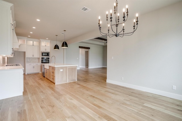 kitchen with backsplash, open floor plan, light countertops, light wood-style floors, and stainless steel appliances