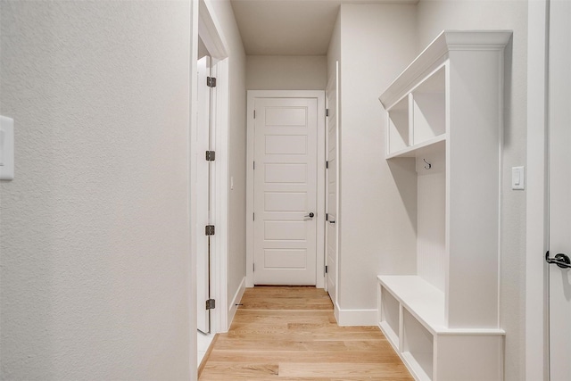 mudroom featuring baseboards, light wood-style floors, and a textured wall