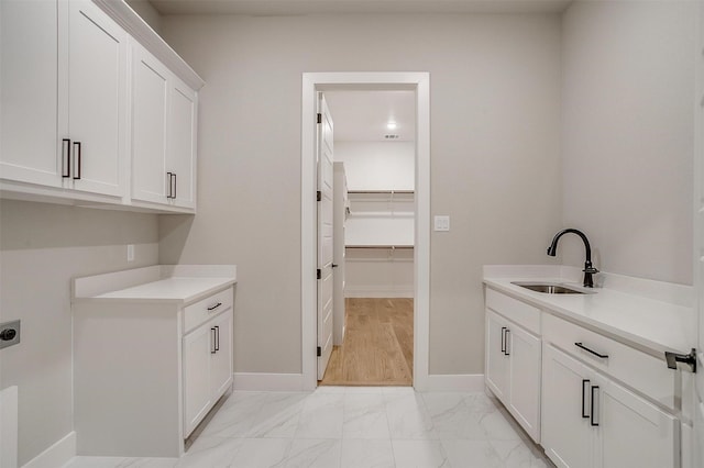 clothes washing area with cabinet space, marble finish floor, hookup for an electric dryer, and a sink