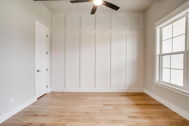 unfurnished room featuring baseboards, light wood-style flooring, and a decorative wall