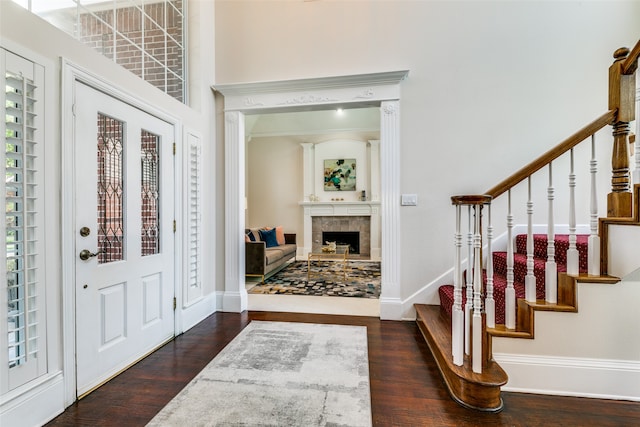 foyer entrance with dark wood-type flooring, plenty of natural light, a tile fireplace, and ornamental molding