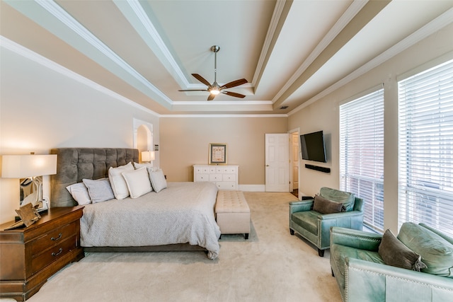 carpeted bedroom with ceiling fan, multiple windows, a raised ceiling, and ornamental molding