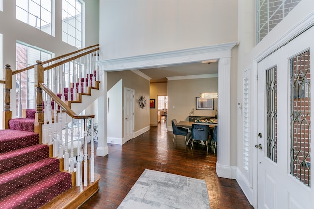 entrance foyer featuring ornamental molding, a towering ceiling, and dark hardwood / wood-style floors