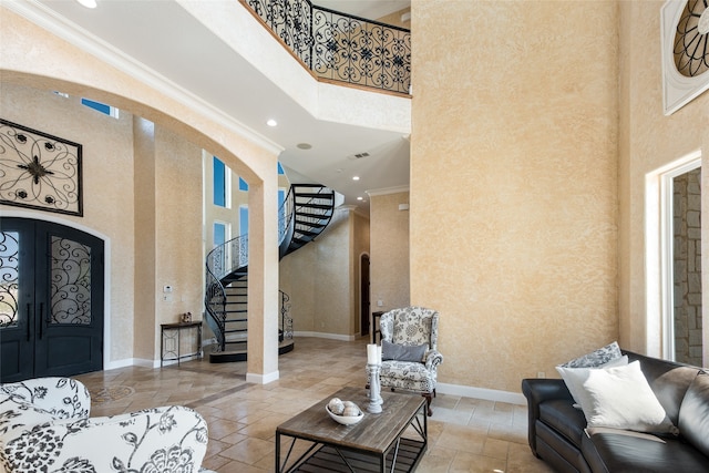 foyer with crown molding, a high ceiling, and french doors