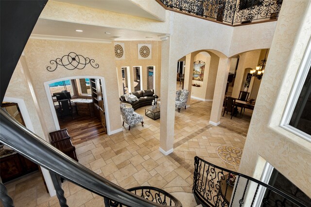 entrance foyer with a notable chandelier, plenty of natural light, crown molding, and a high ceiling