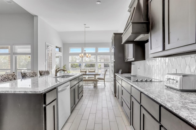 kitchen with dishwashing machine, custom range hood, hanging light fixtures, a center island with sink, and black electric cooktop